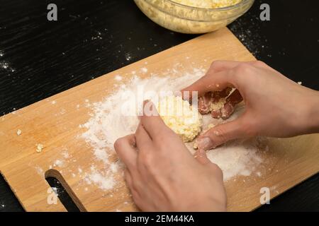 Frauenhände Formen, Formen Hüttenkäse-Pfannkuchen auf einem Holzbrett aus der Nähe, Foto von hinten Stockfoto