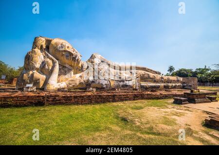 Lotusblumen unterstützen den Kopf des sich rückenden Buddha im Wat Lokaya Sutha, Phra Nakorn Sri Ayutthaya, Thailand. UNESCO-Weltkulturerbe. Stockfoto