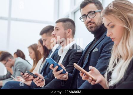 Gruppe von jungen Geschäftsleuten, die ihre Smartphone-Bildschirme betrachten. Stockfoto