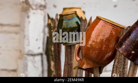 Tontöpfe hängen an einem alten Zaun. Bei bewölktem Tag, natürliches weiches Licht Stockfoto