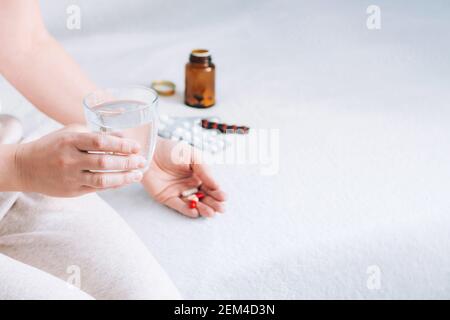 Eine Frau hält ein Glas Wasser und Medikamententabletten in der Hand. Eine kranke Person nimmt Medikamente zu Hause ein. Gesundheit und Medizin. Selektiver Fokus. Speicherplatz kopieren Stockfoto