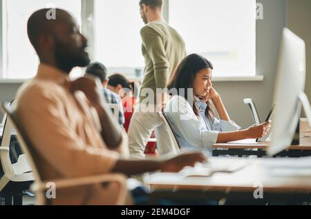 Ernsthafte junge Frau, die sich auf die Büroarbeit konzentriert Stockfoto