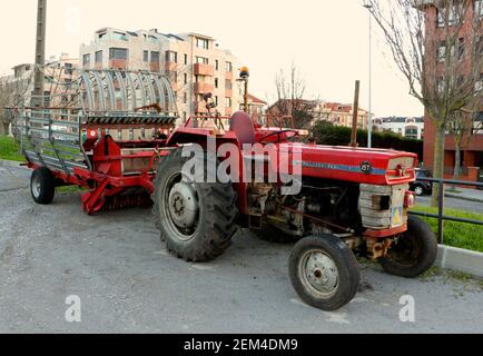 Red Massey Ferguson Traktor geparkt in einem städtischen Gebiet mit landwirtschaftlichen Maschinen Feldhäcksler Anhänger am frühen Morgen Santander Cantabria Spanien Stockfoto