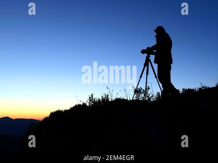 Fotograf Silhouette gegen die aufgehende Sonne in den Bergen Stockfoto