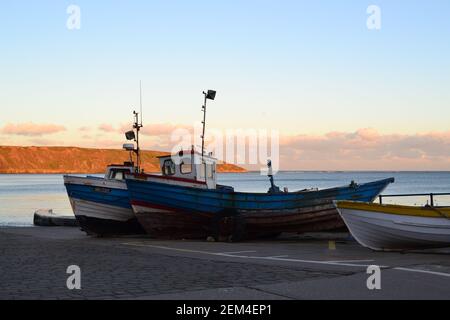 Old Cobles on Coble Landing - Filey Seafront an einem sonnigen Wintertag - ruhige Nordsee, blauer Himmel und Filey Brigg - North Yorkshire - Großbritannien Stockfoto