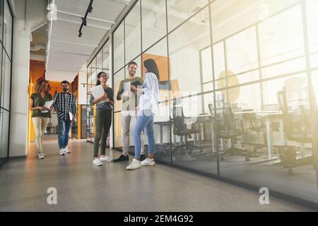 Foto in voller Länge von positiven jungen Mitarbeitern im Bürogebäude Stockfoto