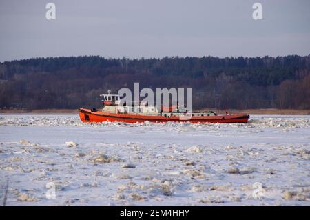 Eisbrecher in der Wintersaison in Betrieb. Zerbrechende Eisschollen auf dem Fluss. Stockfoto