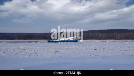 Eisbrecher in der Wintersaison in Betrieb. Zerbrechende Eisschollen auf dem Fluss. Stockfoto