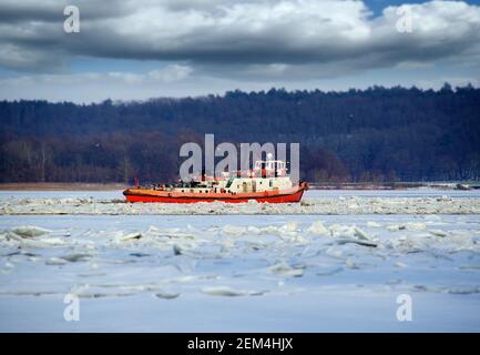 Eisbrecher in der Wintersaison in Betrieb. Zerbrechende Eisschollen auf dem Fluss. Stockfoto