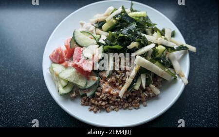 Blick von oben auf frisch zubereitete gesunde Mahlzeit mit gekochtem Buchweizen Salat mit viel Gemüse und gekochtem putenfleisch Stockfoto