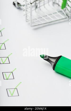 Supermarkt Warenkorb und grüne Markierung auf der Checkliste markiert. Einkaufscheckliste abgeschlossenes Aufgabenkonzept. Stockfoto