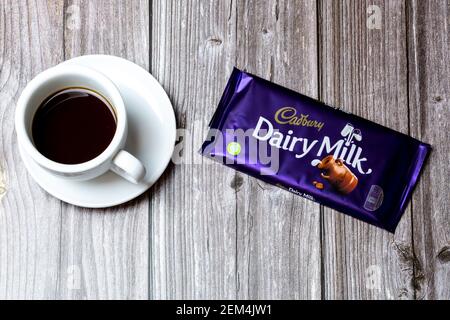 Eine Bar von Cadbury Dairy Milch Schokolade Junge auf einem Holztisch neben einer Tasse Kaffee Stockfoto