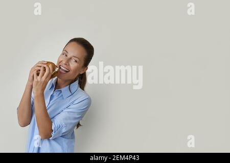 Glückliche junge Frau essen Hamburger und lächeln Stockfoto