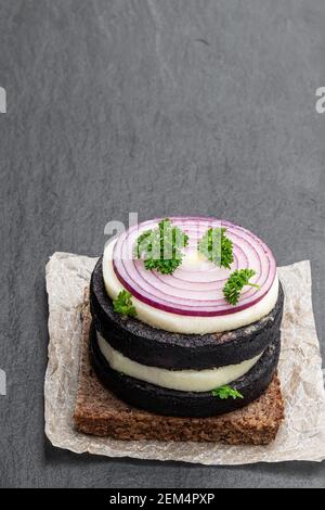 Sandwich mit schwarzem Roggenbrot und schwarzer Puddingwurst Schwarzer Stein Hintergrund Stockfoto