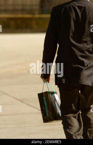 Rückansicht eines Geschäftsmannes mit einer Shopping-Tasche Stockfoto