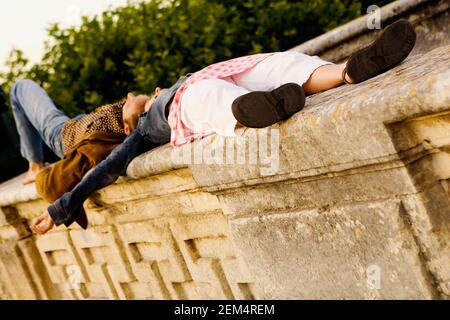 Seitenprofil eines jungen Paares, das auf einem Stein liegt Wand Stockfoto