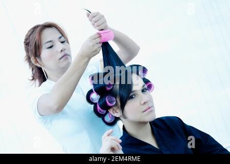Weibliche Friseur setzen Lockenwickler in einem Teenager-Mädchen die Haare Stockfoto