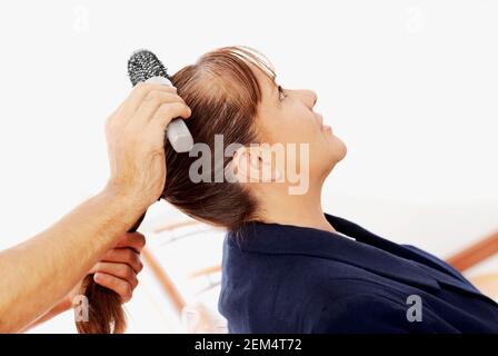 Nahaufnahme von einem Friseur Hand einer reifen Frau Haare zu kämmen