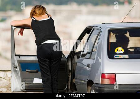 Rückansicht einer Frau, die sich über die Tür von beugt Ein Auto Stockfoto