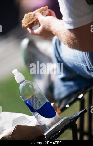 Nahaufnahme eines Mannes, der mit einer Flasche Wodka sitzt Und ein Handy auf dem Tisch Stockfoto