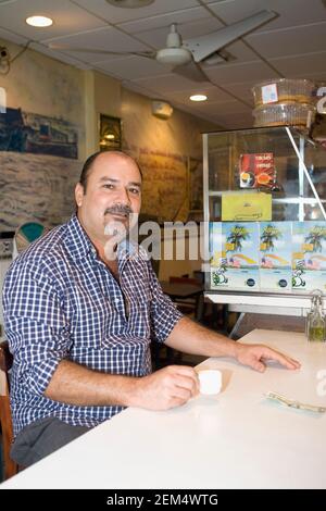 Porträt eines reifen Mannes, der eine Kaffeetasse hält Ein Café und lächelnd Stockfoto