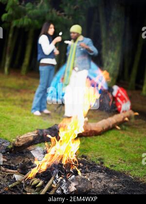 Junges Paar, das in der Nähe eines Lagerfeuers steht Stockfoto