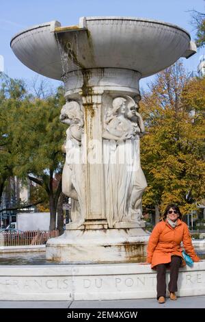 Frau mittleren Erwachsenen sitzt an einem Brunnen, DuPont Circle Fountain, DuPont Circle, Washington DC, Washington State, USA Stockfoto