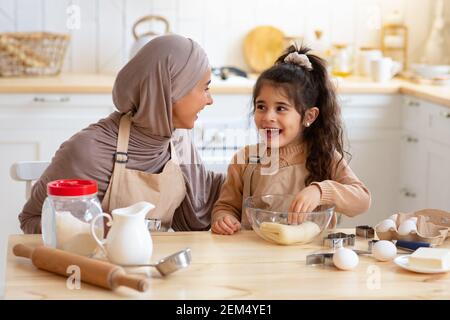 Fröhliche Muslimische Frau In Hijab Backen In Der Küche Mit Ihr Kleine Tochter Stockfoto