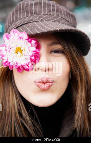 Porträt einer jungen Frau, die sein Auge mit einem bedeckt Blume Stockfoto