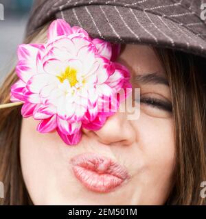 Porträt einer jungen Frau, die sein Auge mit einem bedeckt Blume Stockfoto