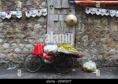 Hanoi, Vietnam - September, 2015: Altes Fahrrad mit Orangen und Taschen an der Wand auf dem Straßenmarkt Stockfoto