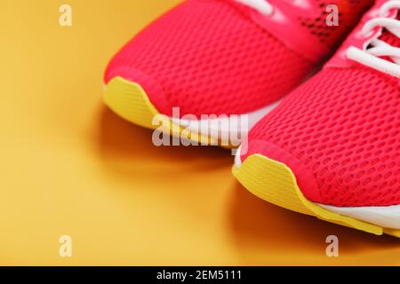 Sport-Sneaker, rosa auf gelbem Hintergrund mit freiem Platz. Blick von oben, minimalistisches Konzept Stockfoto