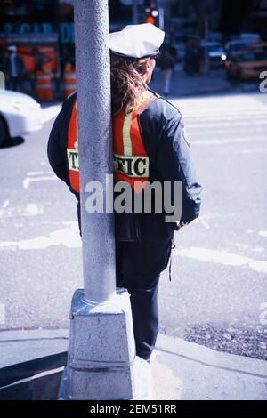 Rückansicht einer Polizistin, die sich an einer Stange lehnt, New York City, New York State, USA Stockfoto
