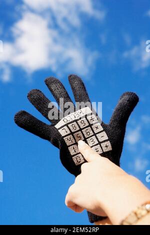 Nahaufnahme einer Person, die einen Handschuh mit Taschenrechner-Tasten trägt Aufgedruckt Stockfoto