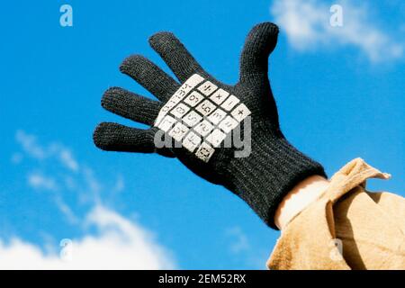 Nahaufnahme einer Person, die einen Handschuh mit Taschenrechner-Tasten trägt Aufgedruckt Stockfoto