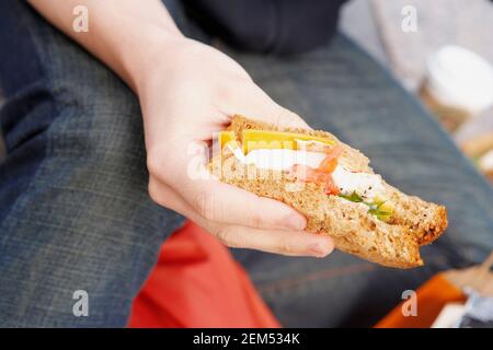 Mittlere Ansicht eines jungen Mannes, der ein Sandwich hält Stockfoto