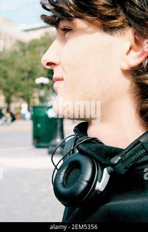 Seitenprofil eines jungen Mannes, der Kopfhörer um seinen herum trägt Hals Stockfoto