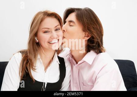 Porträt eines jungen Mannes, der eine junge Frau küsst Ihre Wange Stockfoto