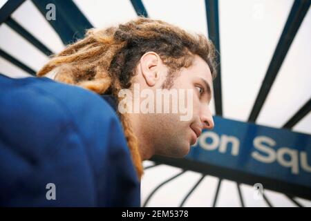 Seitenprofil eines jungen Mannes, der vor einem Schild am Union Square lächelt Stockfoto