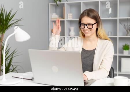 Das Mädchen begrüßt eine Online-Verbindung mit einem Laptop. Junge Studentin studiert aus der Ferne. Stockfoto