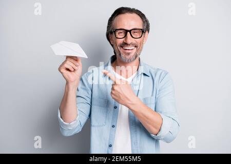 Porträt von gut aussehenden fröhlich reifen Mann hält in der Hand demonstrieren Papierebene isoliert über grauem pastellfarbenem Hintergrund Stockfoto