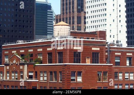 Wassertank auf einem Penthouse auf dem Dach eines älteren Gebäudes zwischen Wolkenkratzern in Midtown, New York, NY, USA Stockfoto