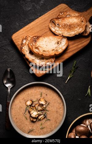 Pilzsahnesuppe serviert mit geröstetem Brot auf grauem Hintergrund, Draufsicht Stockfoto