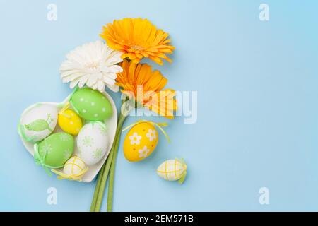 Ostern Grußkarte mit Gerbera Blumen und bunten ostereiern. Draufsicht flach lag mit Platz für Ihre Grüße Stockfoto