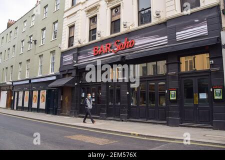 Ein Mann mit einer schützenden Gesichtsmaske geht während der Coronavirus-Sperre an der geschlossenen Bar Soho in der Old Compton Street vorbei. London, Großbritannien. Stockfoto