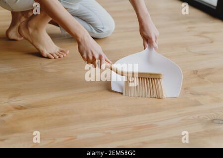 Nahaufnahme der Frau mit Bürste und Kehrschaufel fegenden Boden zu Hause. Frühjahrsputz-Konzept. Stockfoto