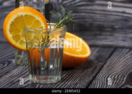 Gin in einem Glas. Garniert mit einer Scheibe Orange und Rosmarin. Stockfoto