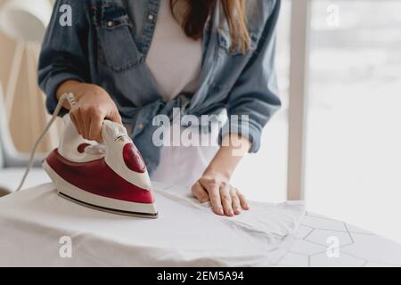 Nahaufnahme der Frau, die Kleidung auf dem Bügelbrett zu Hause bügelt. Stockfoto