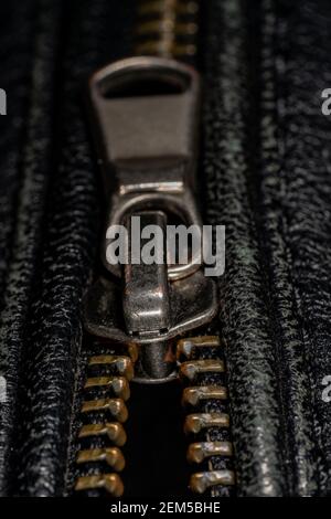 Detail der Verriegelung Reißverschluss auf schwarzem Leder Jacke. Nahaufnahme der Makro-Aufnahme mit lokalem Fokus. Vertikale Makrofotografie. Stockfoto