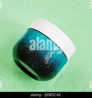 Natürliche Bio-Creme in blauem Glas, Wasserblasen, heller Hintergrund. Hautpflege, Feuchtigkeitscreme, minimalistischer Stil Stockfoto